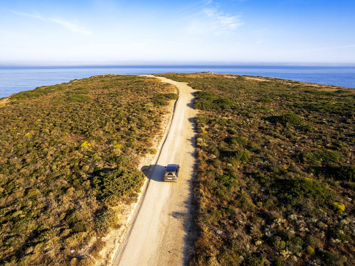 A car drives on a dusty road in the Algarve