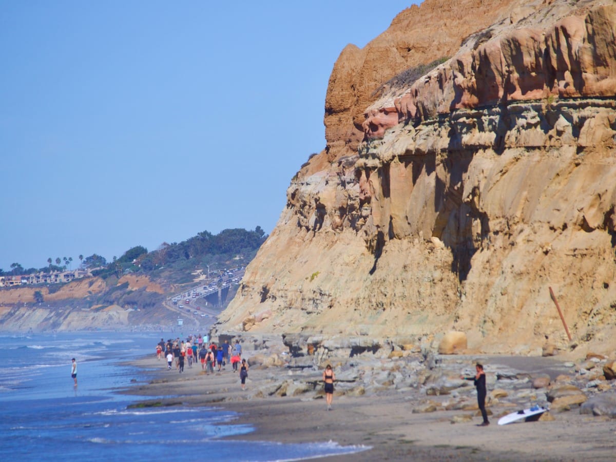 Surfer under the SoCal cliffs